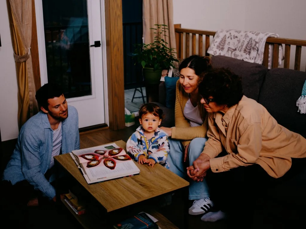 A family sits at a coffee table in a living room